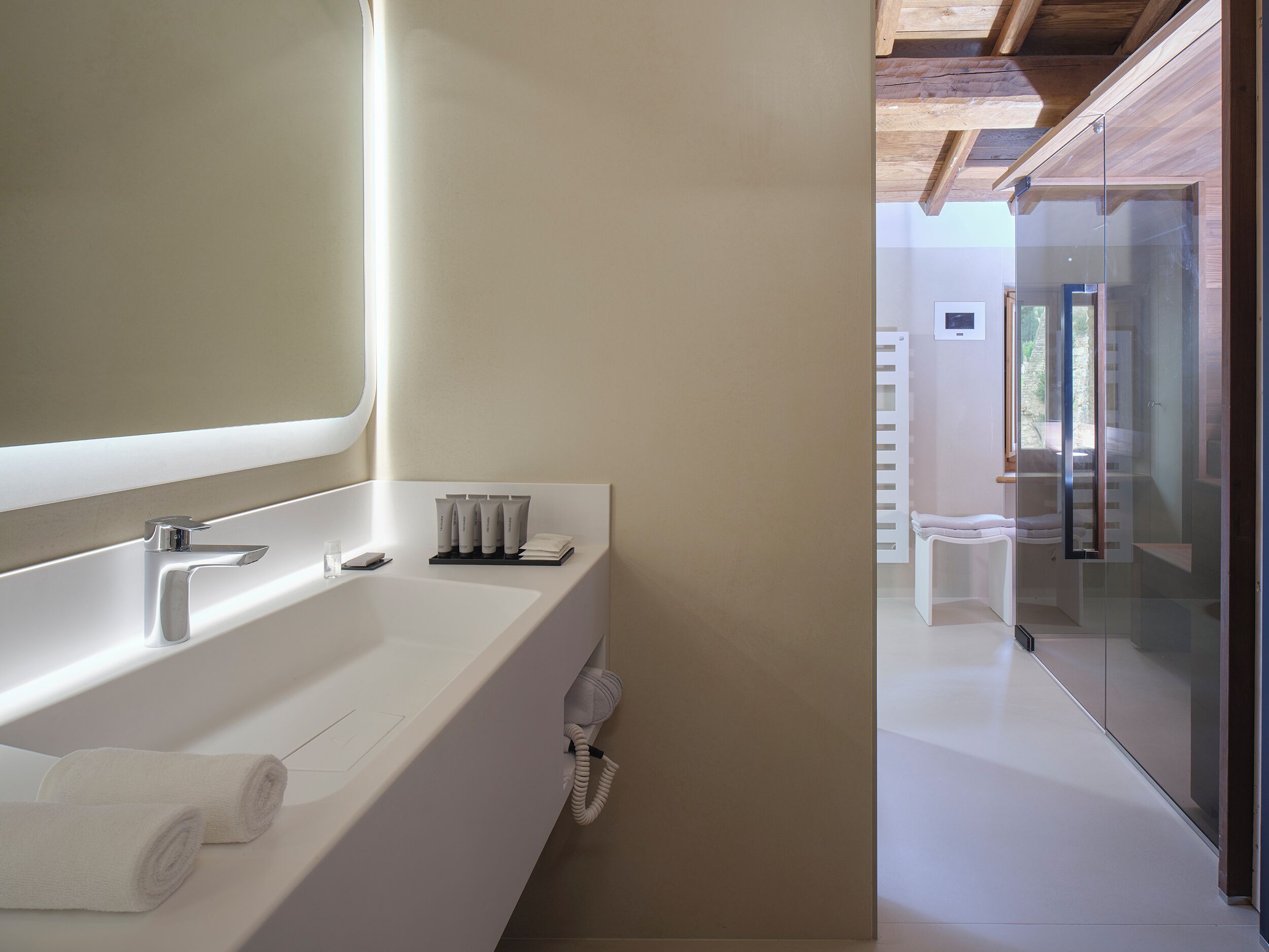 Une salle de bain moderne avec un grand lavabo blanc, un miroir et une cabine de douche en verre.