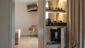 A hotel room with a bed, a chair, a minibar, a television, and a coffee machine. - Ascesi Resort (Assisi)