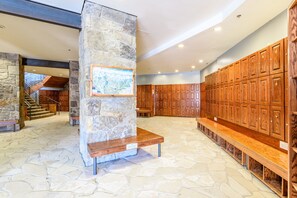 A lobby with stone walls, wooden benches, and a map display.