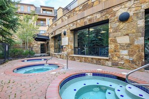 A spa area with two hot tubs and a stone wall. - Large 2 Bdrm on Main St/Peak 9 Base; Hot Tubs/Pool (Breckenridge)