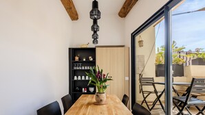 Un coin repas avec une table en bois, des chaises noires, une bibliothèque noire et une plante en pot.