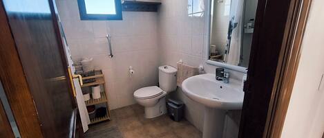 Een kleine badkamer met toilet, wastafel en een klein raam.