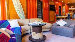 A cozy living area with a sofa, a coffee table, and a surfboard leaning against the wall. - Pousada Alma Brava (Itajai)