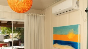 A bedroom with a bed, a painting, an air conditioning unit, and a view of the outside. - Pousada Alma Brava (Itajai)