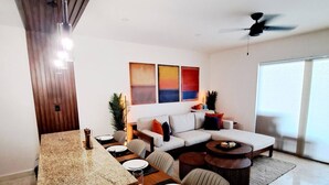 A modern living room with a dining area, a sofa set, and a ceiling fan.