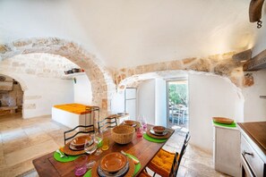 Un comedor con un arco de piedra, una mesa de madera dispuesta para cuatro personas y vistas al exterior.