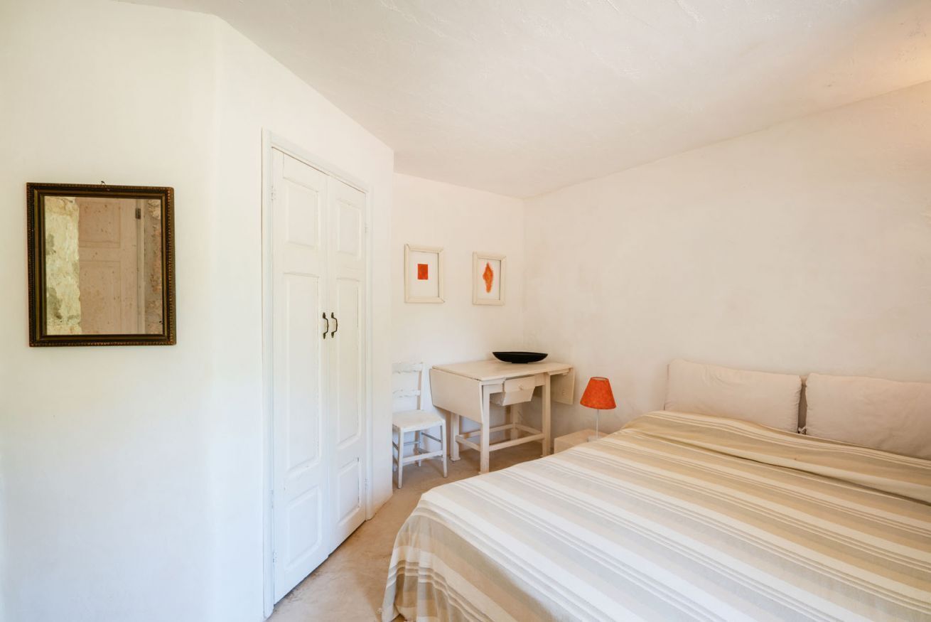Une pièce comprenant un lit, un bureau, une chaise et une porte.