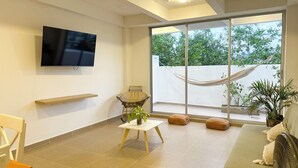 A modern living room with a flat-screen TV, a hammock, a sofa, and a fan.