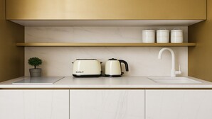 A kitchen with white marble cabinets, a dual-tone countertop, a potted plant, a toaster, a kettle, and three white containers labeled "TEA," "COFFEE," and "SUGAR." - Studio moderne a Opera (Paris)