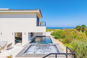 A modern house with a swimming pool, a balcony, and a view of the ocean. - Modern Golf‑Front Villa w/ Heated Pool, Hot Tub, Game Room | Club Campestre (San Jose del Cabo)