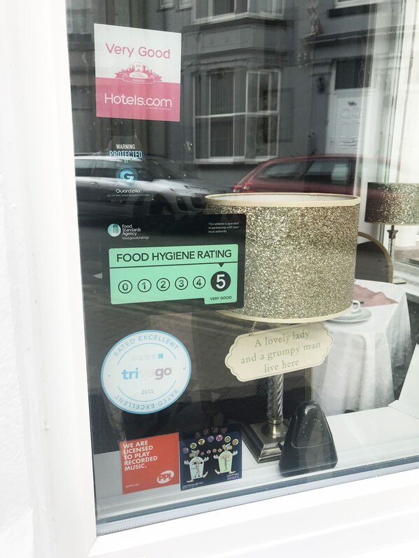 A window display with a food hygiene rating of 5, a 'Very Good' Hotels.com rating, and a 'Rated Excellent' by TripAdvisor. - AYSGARTH HOUSE (Blackpool)
