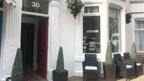 A white building with a red door, a sign reading "No Vacancies", and outdoor wicker chairs. - AYSGARTH HOUSE (Blackpool)