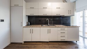 A modern kitchen with white cabinets, a black backsplash, and a stainless steel sink. - Saranda Beach Living - 1BR Apartment (Sarandë)