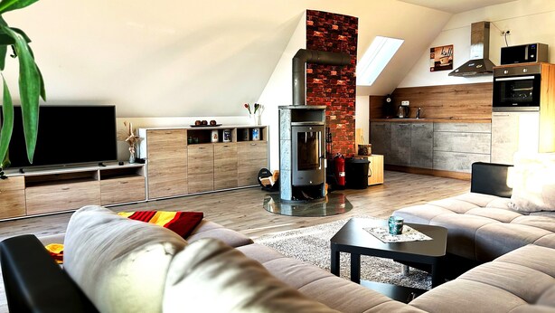 Una sala de estar moderna con chimenea, televisor y zona de cocina.