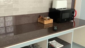 Un plan de travail de cuisine avec un four à micro-ondes, un grille-pain et un panier rempli d’objets décoratifs.