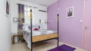 Une chambre à coucher avec un lit à baldaquin, un tapis violet et un mur rose.
