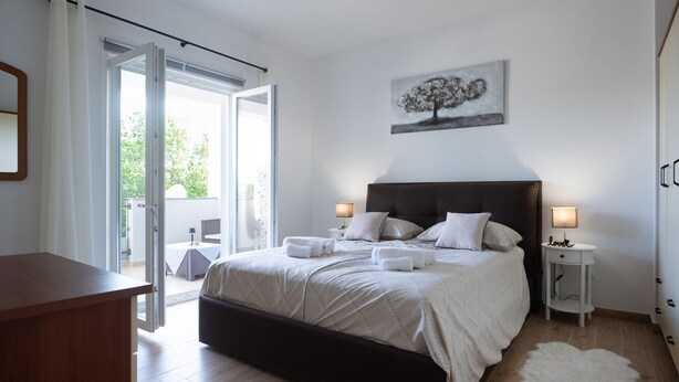 Een slaapkamer met een groot bed, een nachtkastje, een bureau en uitzicht op de omgeving.