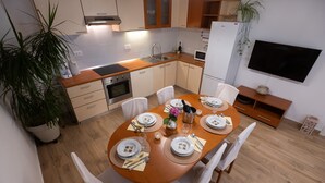Een moderne keuken met houten kastjes, een ingebouwde oven en een magnetron. Er staat een eettafel gedekt met borden, glazen en bestek.