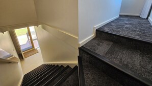 Eine Treppe mit dunklem Teppich und weißer Wand.