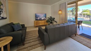 Una sala de estar moderna con un sofá gris, un mueble de madera y un televisor de pantalla plana.