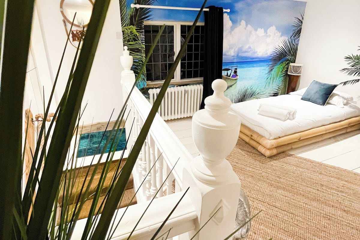 Une chambre avec vue sur l’océan, un lit blanc, une chaise blanche et une cheminée blanche.