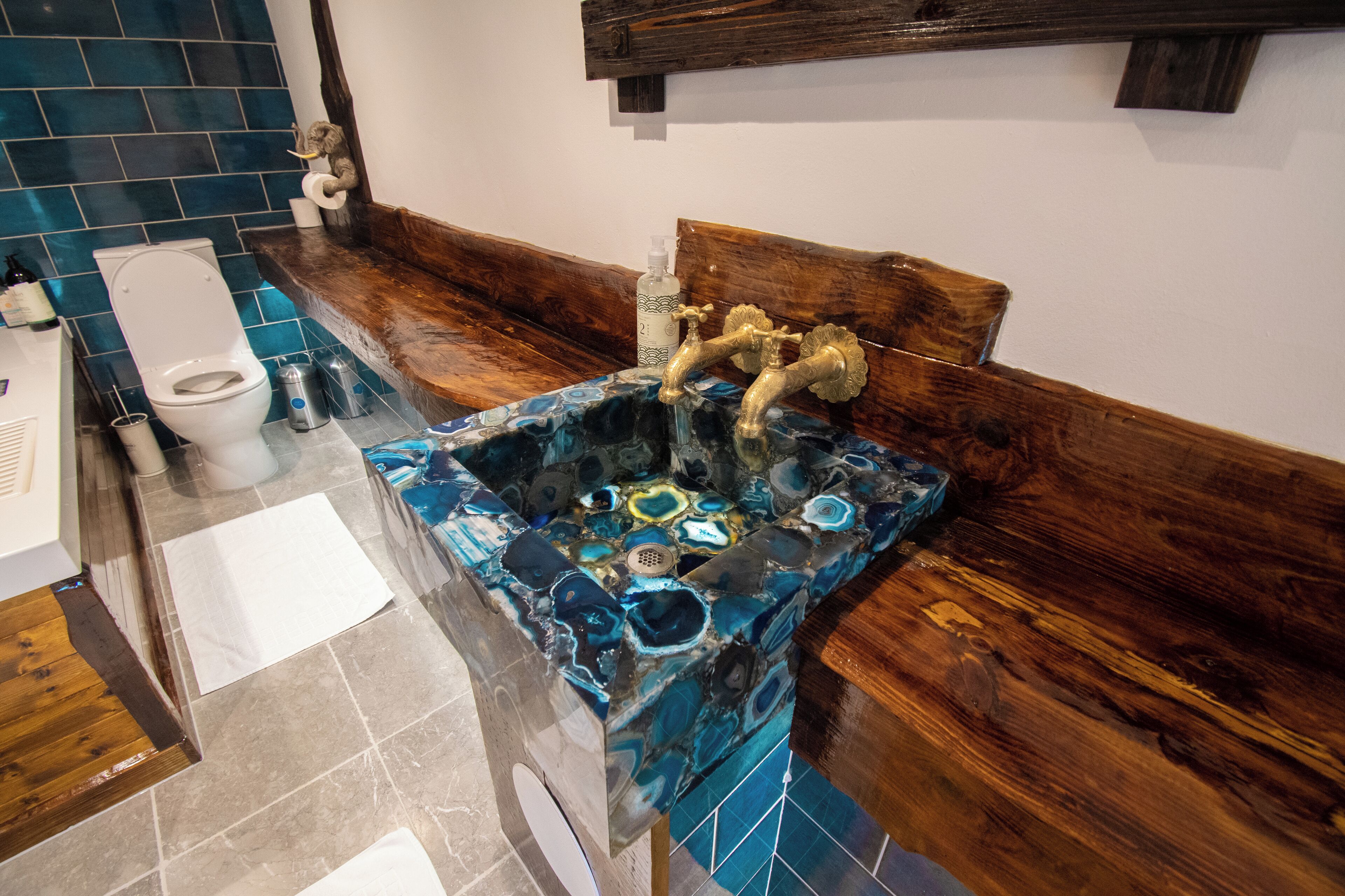 Un bagno con lavabo in marmo, mobile bagno in legno e water.