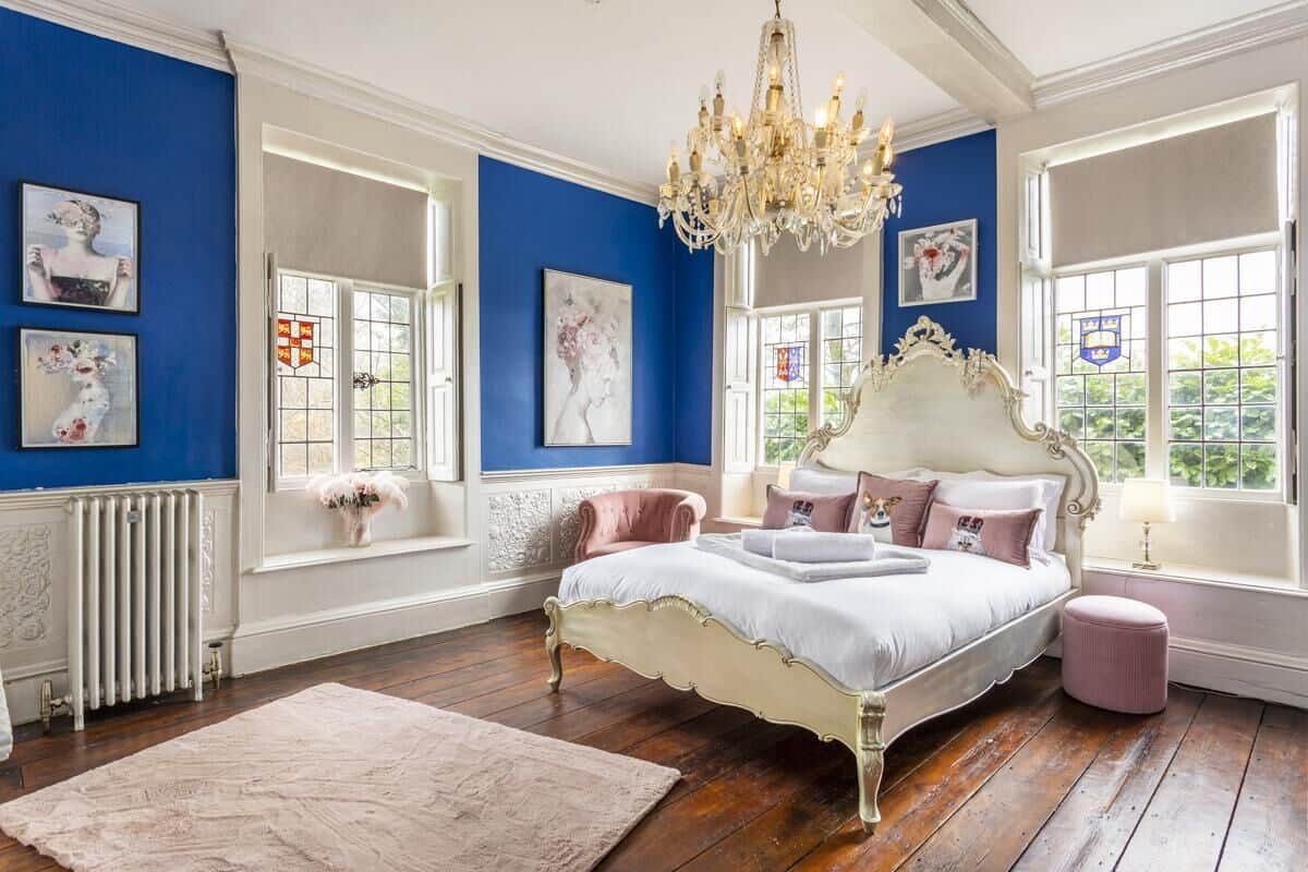 Une chambre à coucher avec un grand lit, un lustre et des œuvres d’art accrochées aux murs.