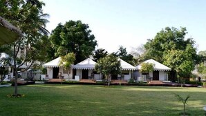 A row of white tents with a grassy lawn in the foreground. - Pichola Vilas (Udaipur)