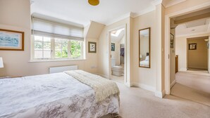 Une chambre à coucher avec un grand lit, une fenêtre avec des stores, un miroir et une porte donnant sur une salle de bain.