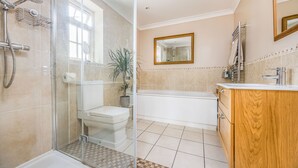 Une salle de bain moderne avec une douche à l’italienne en verre, des toilettes, une baignoire et un meuble-lavabo en bois.