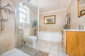 Une salle de bain moderne avec une douche à l’italienne en verre, des toilettes, une baignoire et un meuble-lavabo en bois.