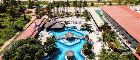 Un resort con una gran piscina, una playa y un edificio de techo rojo.