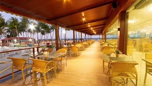 Un espace extérieur abrité, aménagé pour les repas, avec des meubles en osier et une vue sur la plage.