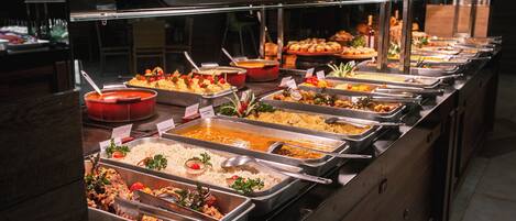 A buffet with various food options, including rice, pasta, and salads.