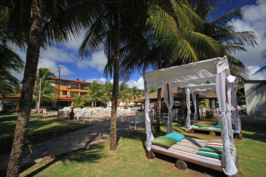 Een resort met een hemelbed, palmbomen en een zwembad.