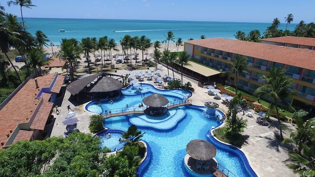 Un complexe hôtelier doté d’une grande piscine, d’une plage et d’un bâtiment comportant de nombreux balcons.