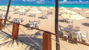 Une vue sur la plage, avec des palmiers, des chaises de plage et des parasols.