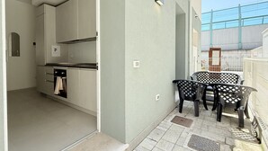 A modern kitchen with built-in appliances, a dining area with outdoor chairs, and a view of a bridge. -  SE192 - Senigallia, new two-room apartment 50 meters from the sea (Senigallia)