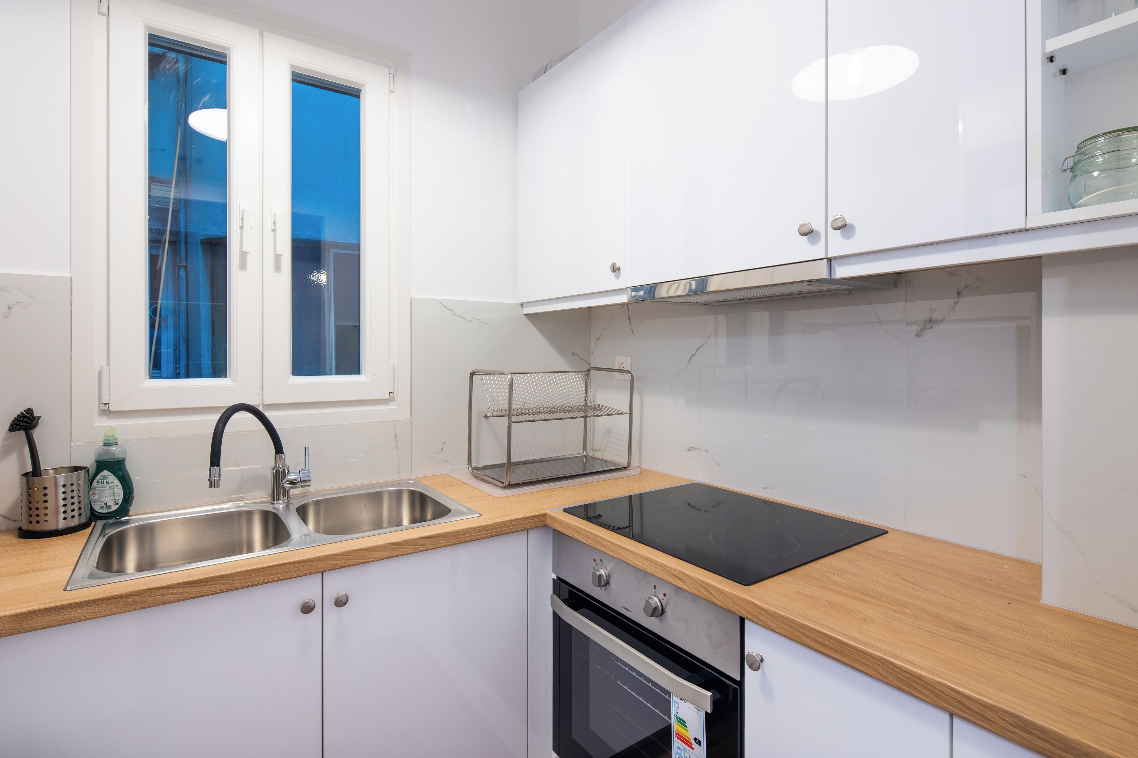 Een moderne keuken met twee spoelbakken, een zwart inductiekookveld en een ingebouwde oven.