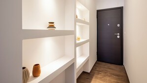 A hallway with white shelves and a dark door. - Alex's 2-Bedroom Apartment in Athens (Athens)