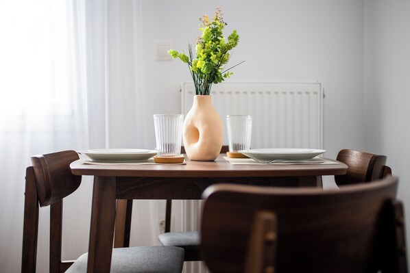 Une table à manger avec un vase de fleurs, des assiettes et des verres.