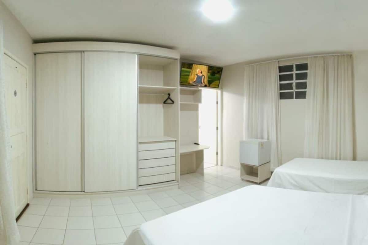 Une chambre avec deux lits, une armoire, un bureau et un téléviseur.