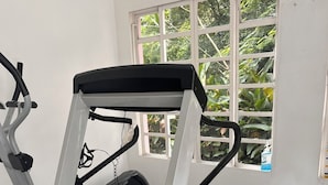 Un gimnasio con cinta de correr, elíptica y bicicleta estática.