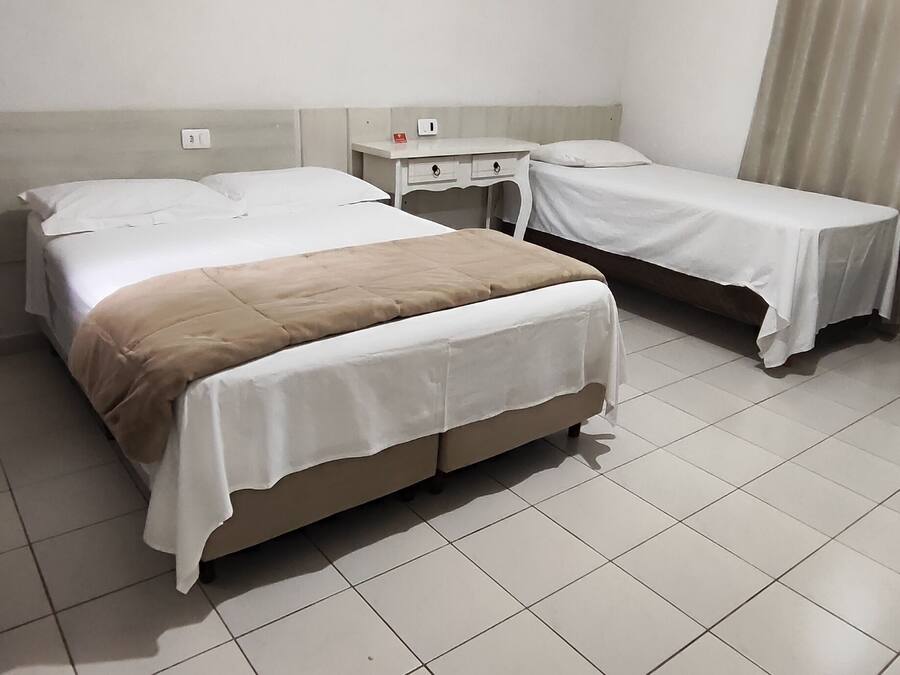 Una habitación de hotel con dos camas, una mesita de noche pequeña y un enchufe en la pared.
