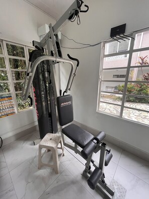 Un gimnasio con una bicicleta estática, una banca y máquinas de pesas.