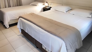 Habitación de hotel con dos camas, una mesita de noche con lámpara y un equipo de aire acondicionado en la pared.