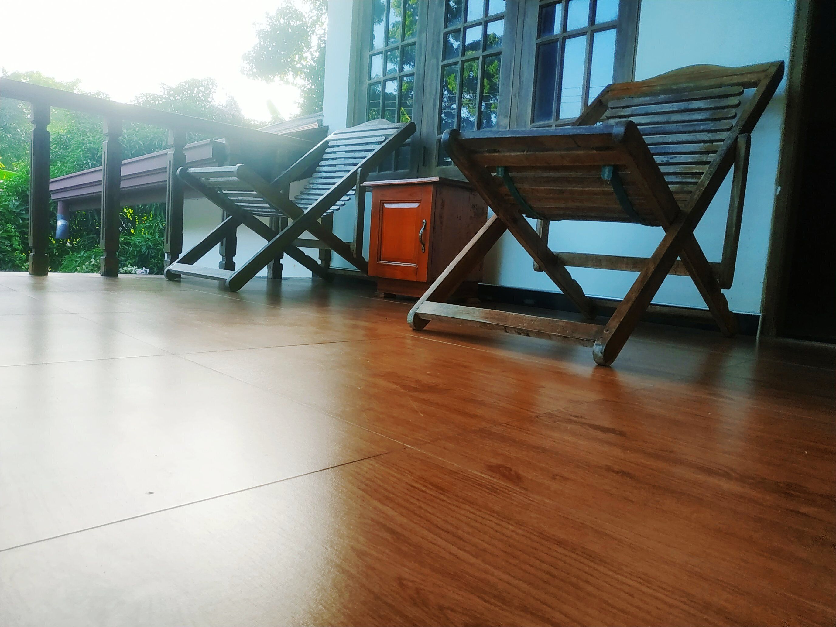 A room with a wooden floor, a wooden chair, and a small orange cabinet.