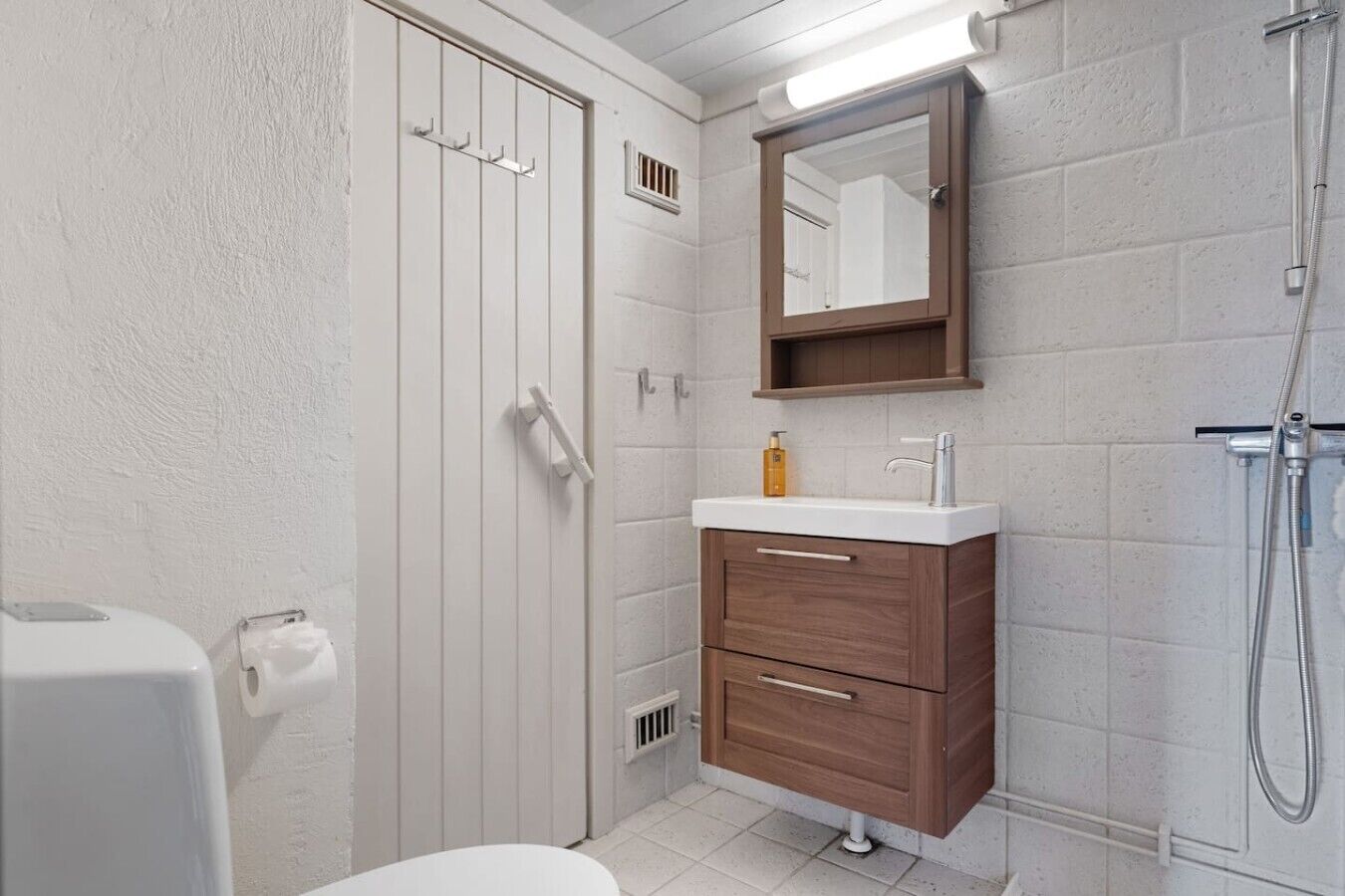 A bathroom with a toilet, a sink with a mirror above it, and a shower.