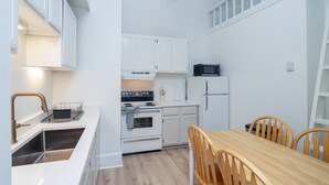 A compact kitchen with white cabinets, a stainless steel sink, a stove, and a microwave. - Stone Alley Condo 1 Bedroom Condo (Telluride)