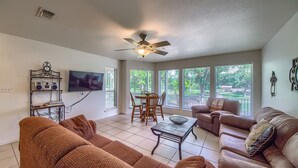 A living room with a ceiling fan, a TV mounted on the wall, a dining table with chairs, and two couches. - Ww D101 2 Bedroom Condo (New Braunfels)
